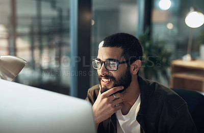 Buy stock photo Shot of a young businessman using a computer during a late night in a modern office