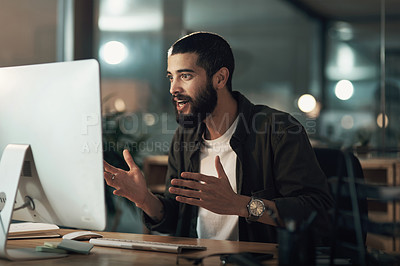 Buy stock photo Shot of a young businessman looking shocked while using a computer during a late night at work