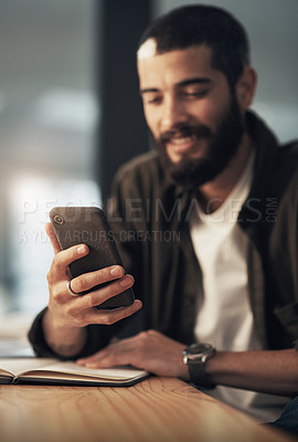 Buy stock photo Shot of a young businessman using a smartphone during a late night at work