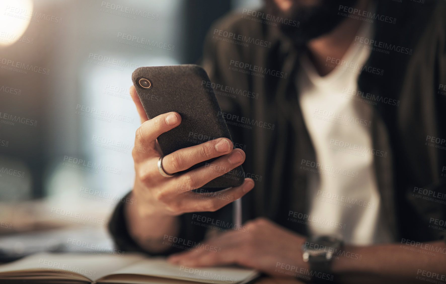 Buy stock photo Shot of an unrecognisable businessman using a smartphone during a late night at work