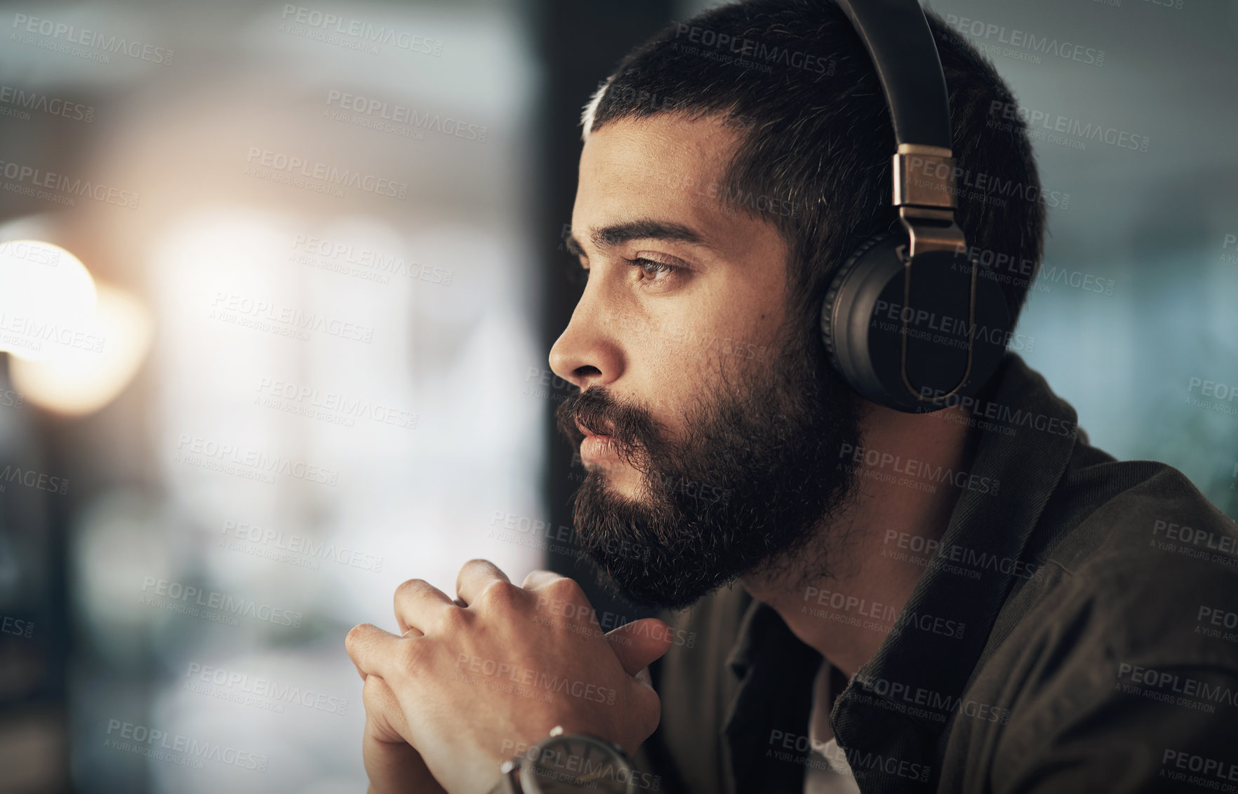 Buy stock photo Shot of a young businessman using headphones during a late night at work