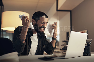 Buy stock photo Shot of a young businessman feeling stressed while working late at night in a modern office