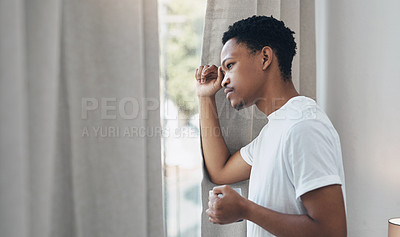 Buy stock photo Shot of a young man having coffee and looking outside his bedroom window at home