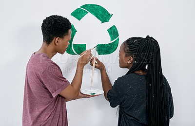 Buy stock photo Shot of a young couple painting a recycle symbol on a wall