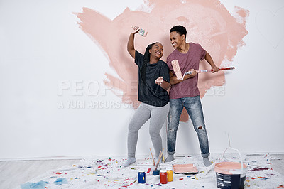 Buy stock photo Shot of a young couple painting a wall pink