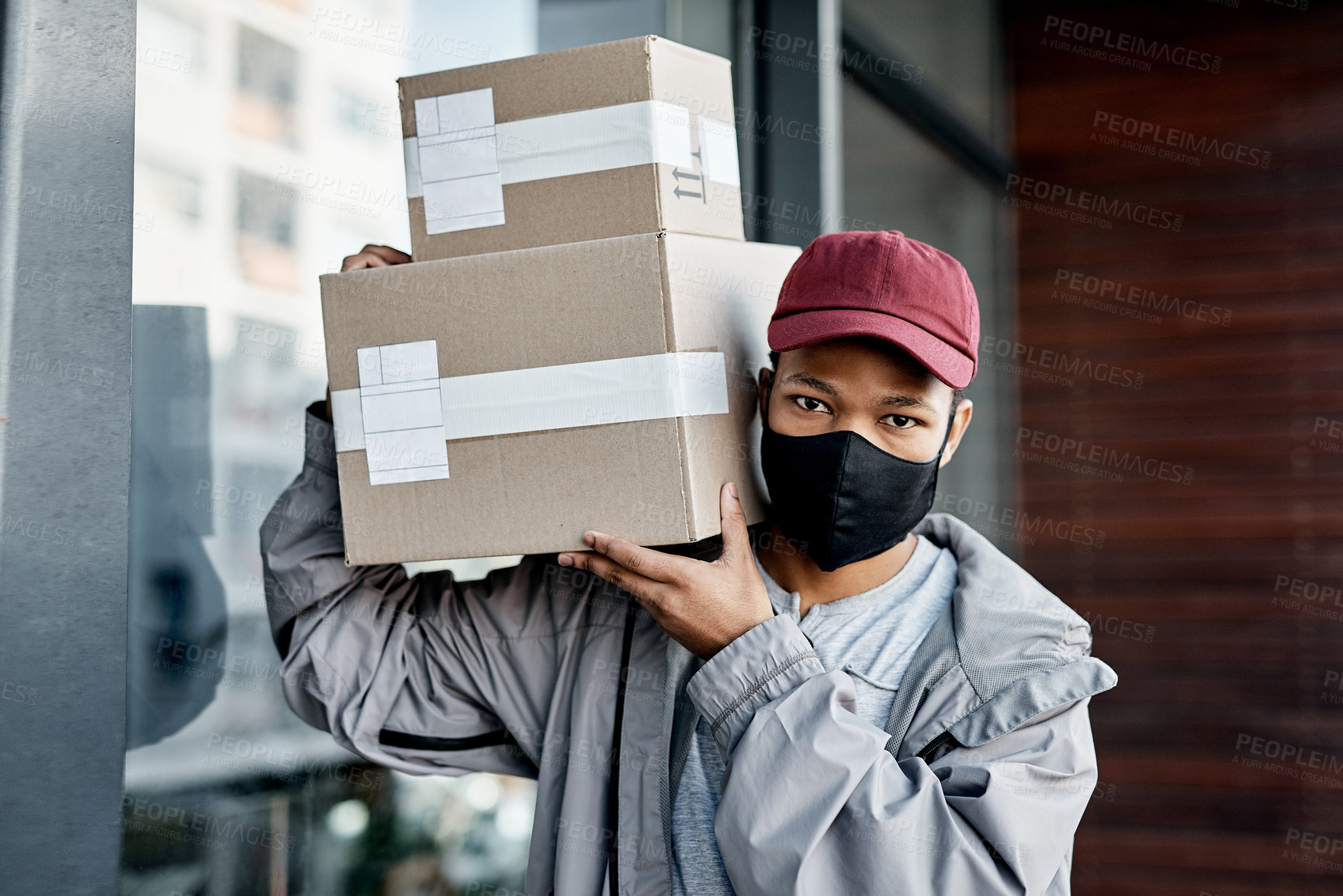 Buy stock photo Shot of a masked young man delivering a package to a place of residence