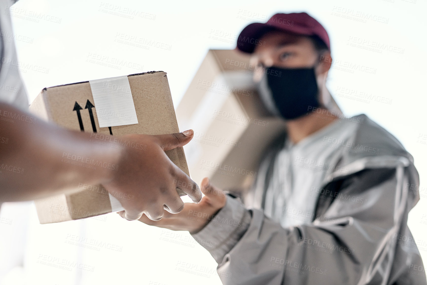 Buy stock photo Shot of a masked young man delivering a package to a customer at home