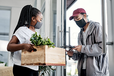 Buy stock photo Shot of a masked young man delivering fresh produce to a customer at home