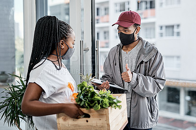 Buy stock photo Shot of a masked young man showing thumbs up while delivery fresh produce to a customer at home