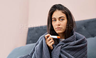 Buy stock photo Shot of a young woman taking her temperature while recovering from an illness in bed at home