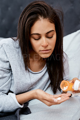 Buy stock photo Shot of a young woman taking medication while recovering from an illness in bed at home