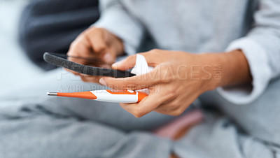 Buy stock photo Shot of an unrecognisable woman using a smartphone and thermometer while recovering from an illness at home