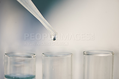 Buy stock photo Closeup shot of liquid from a dropper falling into test tubes in a lab