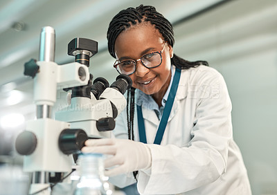 Buy stock photo Portrait of a young scientist using a microscope in a lab