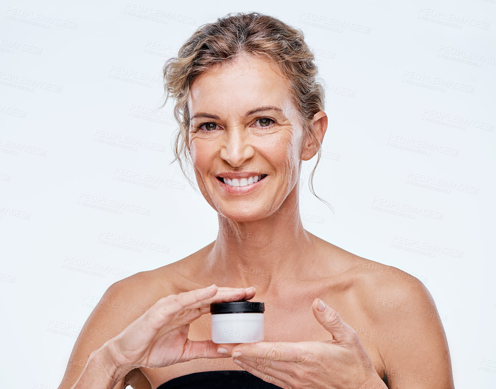 Buy stock photo Shot of a mature woman holding up a beauty product against a while background