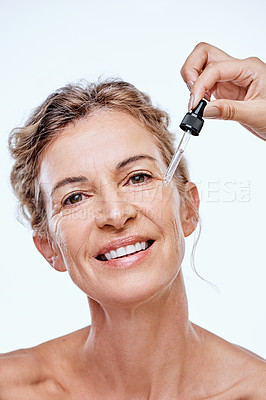 Buy stock photo Shot of a mature woman posing with a serum dropper against her face