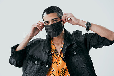 Buy stock photo Studio shot of a young man putting on a face mask against a grey background