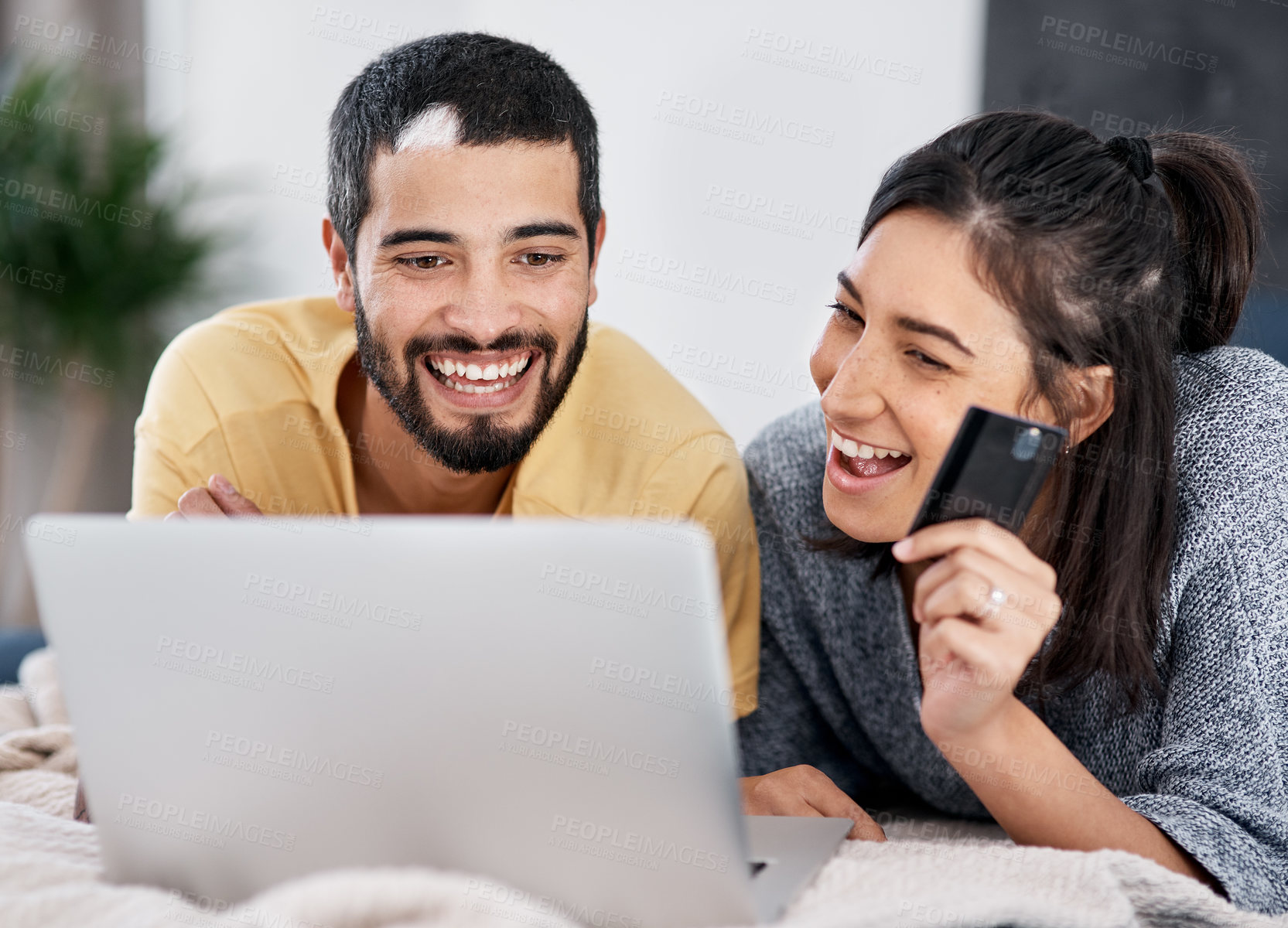 Buy stock photo Shot of a young couple using a laptop and credit card together in bed