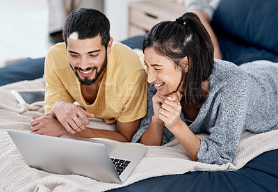 Buy stock photo Shot of a young couple using a laptop together in bed