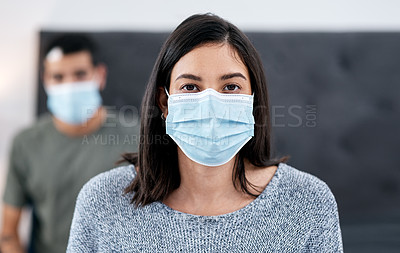 Buy stock photo Shot of a masked young couple recovering from an illness in bed at home