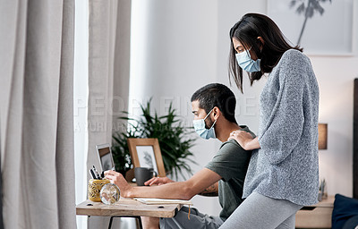 Buy stock photo Shot of a masked young couple working from home