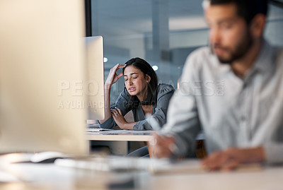 Buy stock photo Shot of a young woman feeling stressed while using a headset and computer late at night in a modern office