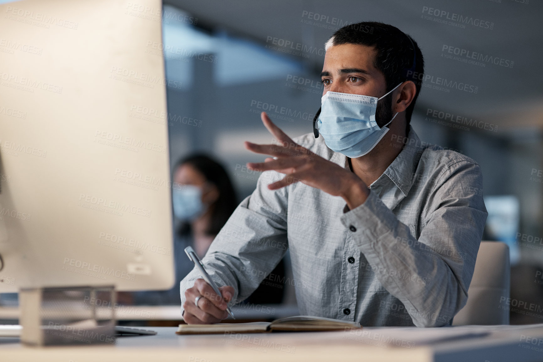 Buy stock photo Call center, man and communication with mask at computer while writing notes for advice, customer service and sales. Male telemarketing agent, virus protection and desktop for consulting questions