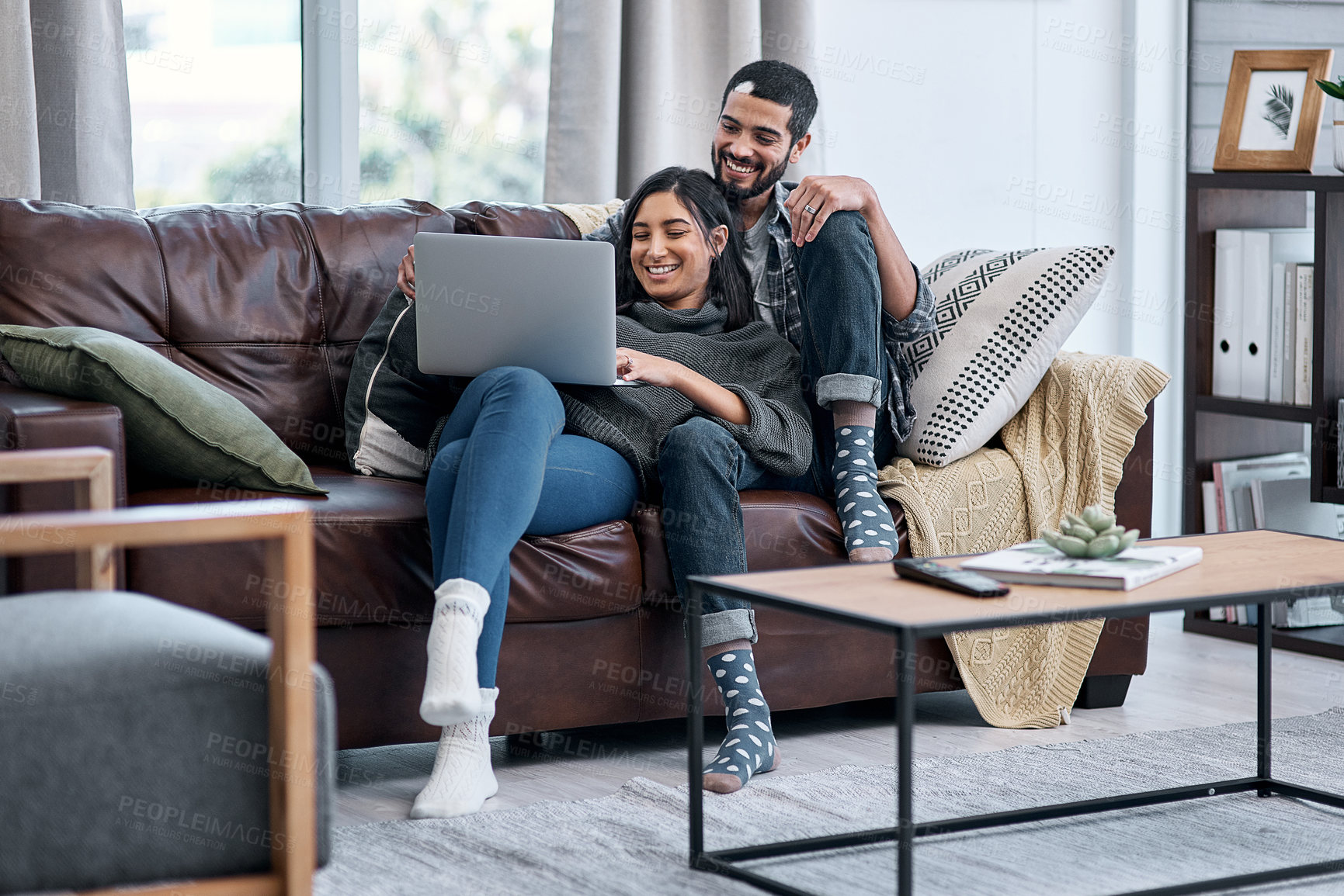 Buy stock photo Shot of a young couple using a laptop while relaxing on the sofa at home