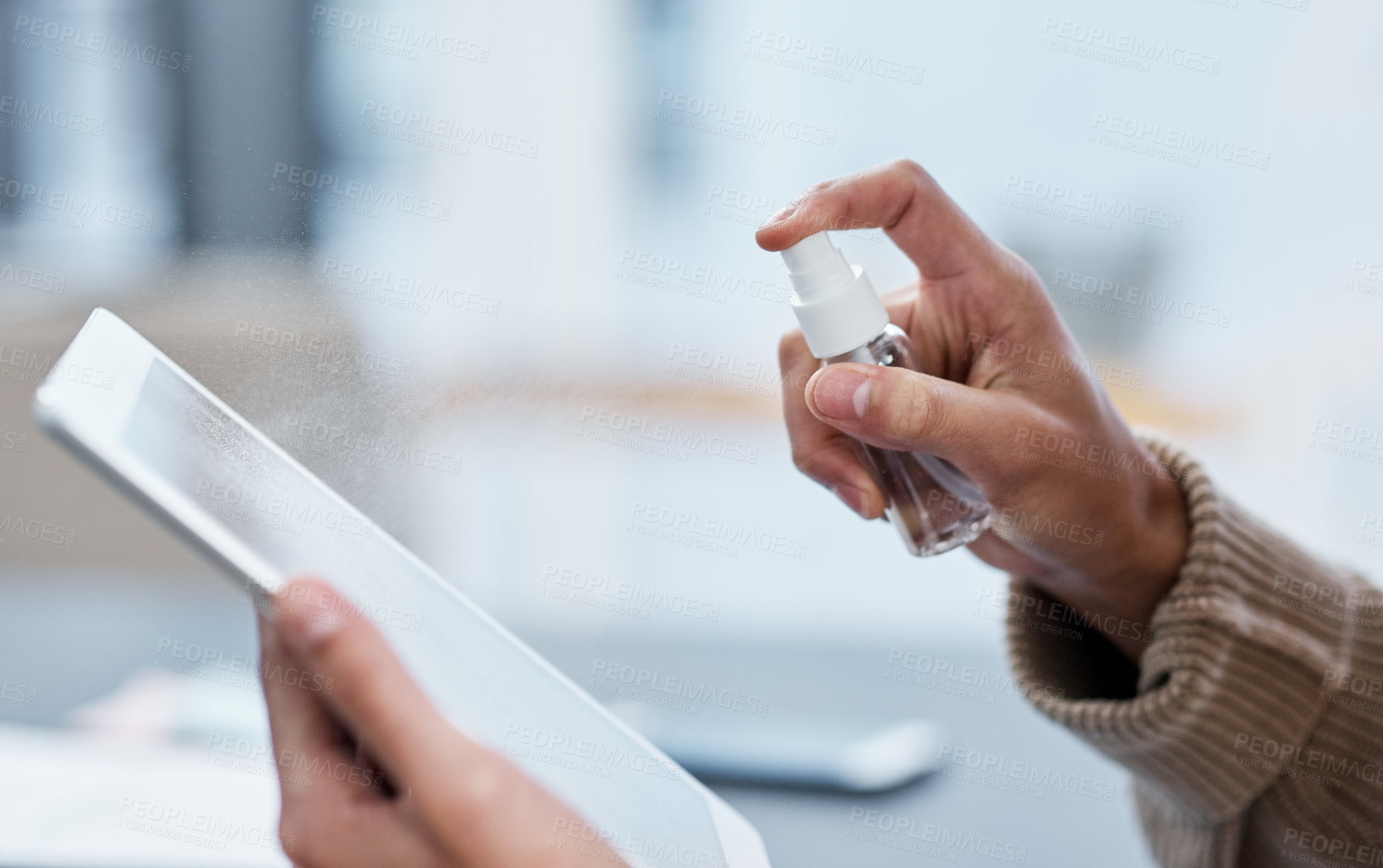 Buy stock photo Shot of an unrecognisable man disinfecting his digital tablet while working from home