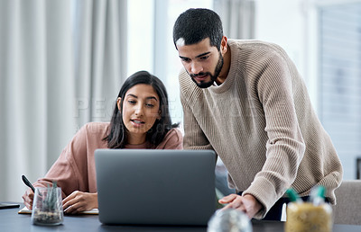 Buy stock photo Shot of a young man and woman using a laptop while working from home