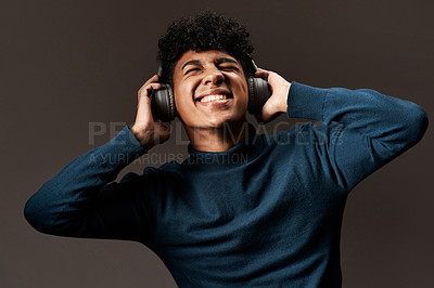 Buy stock photo Studio shot of a young man using headphones against a grey background