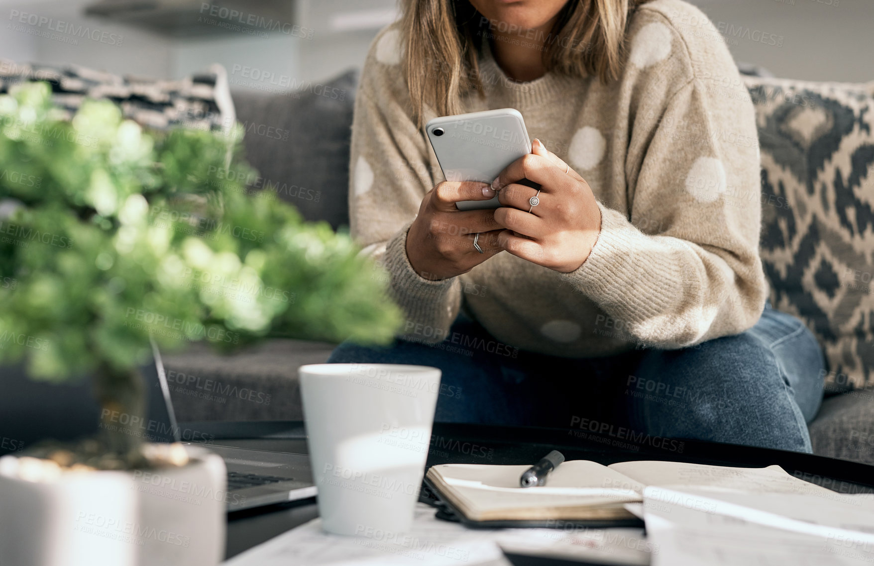 Buy stock photo Cropped shot of a young woman using her cellphone while working from home