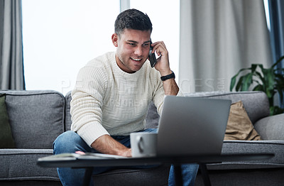 Buy stock photo Shot of a young man using a laptop and smartphone while working from home