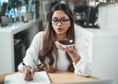 Buy stock photo Shot of a businesswoman using her cellphone and notebook while working from a cafe