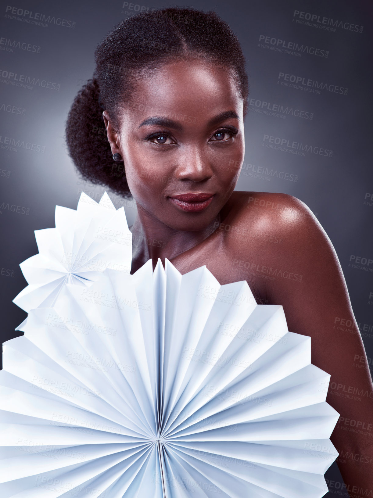 Buy stock photo Studio portrait of a beautiful young woman posing with origami fans against a black background