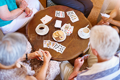 Buy stock photo High angle shot of a group of seniors playing cards around a table in their retirement home