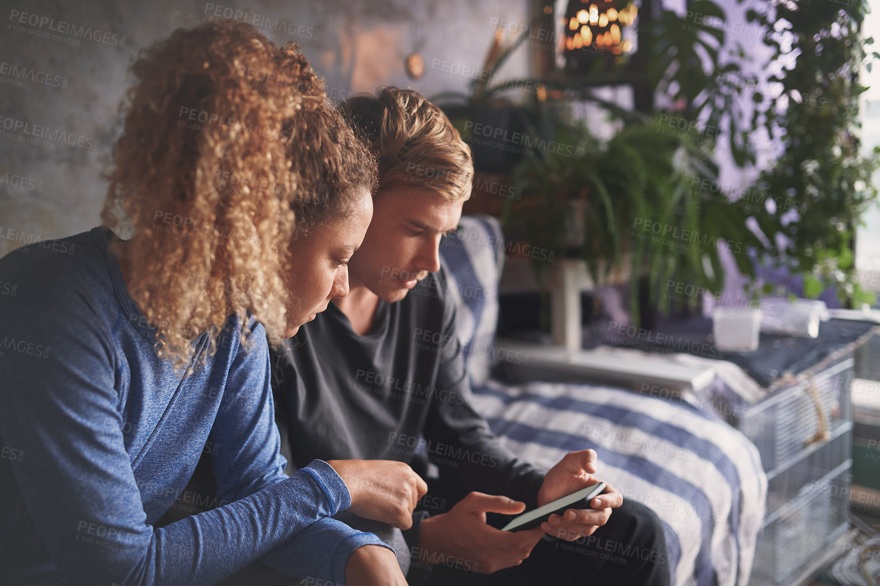 Buy stock photo Shot of a young couple using a smartphone on the sofa at home