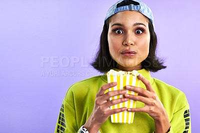 Buy stock photo Studio shot of a beautiful young woman eating popcorn against a purple background