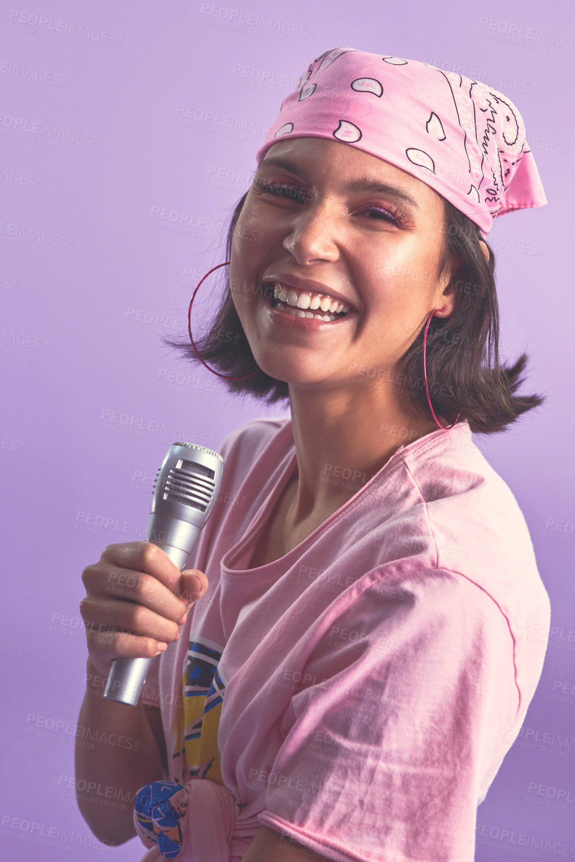 Buy stock photo Studio shot of a beautiful young woman singing with a microphone against a purple background