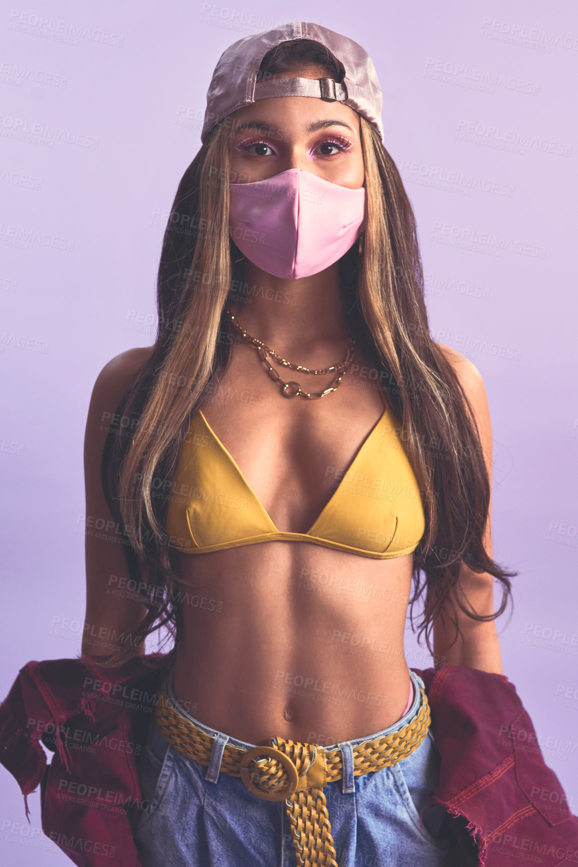 Buy stock photo Studio shot of a beautiful young woman wearing a face mask against a purple background