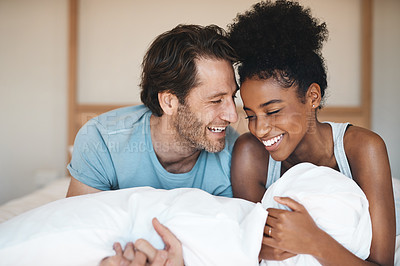 Buy stock photo Happy couple, bed and laughing in relax for morning, bonding or intimate relationship at home. Interracial man and woman smiling with laugh in joyful happiness or relaxing weekend together in bedroom