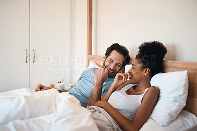 Buy stock photo Happy, silly and goofy couple bonding in bed, sharing intimate relationship joke and moment. Young interracial husband and wife laughing, loving and enjoying lazy morning relaxing indoors together