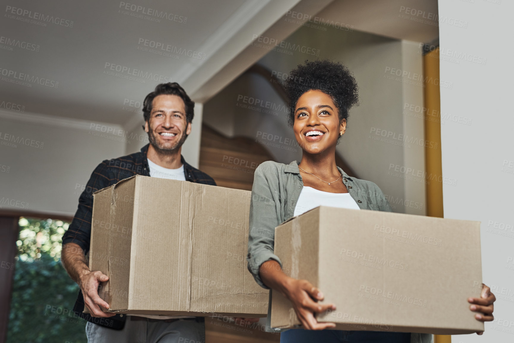 Buy stock photo New house, moving and happy couple carrying boxes while feeling proud and excited about buying a house with a mortgage loan. Interracial husband and wife first time buyers unpacking in dream home 
