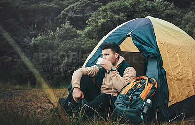 Buy stock photo Shot of a young man drinking coffee while camping in the wilderness