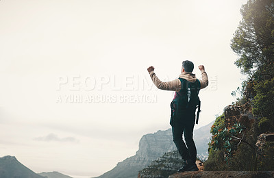Buy stock photo Rearview shot of a young man standing with his arms outstretched while hiking on a mountain