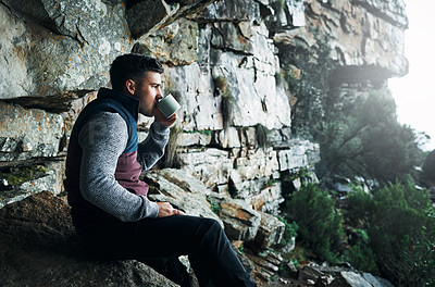 Buy stock photo Shot of a young man drinking coffee while hiking through the mountains