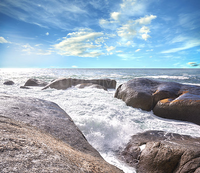 Buy stock photo Copy space ocean view of beach with foamy sea water crashing onto boulders and rocks on a peaceful summer vacation in South African. Texture and detail of scenic coastline and cloudy blue sky