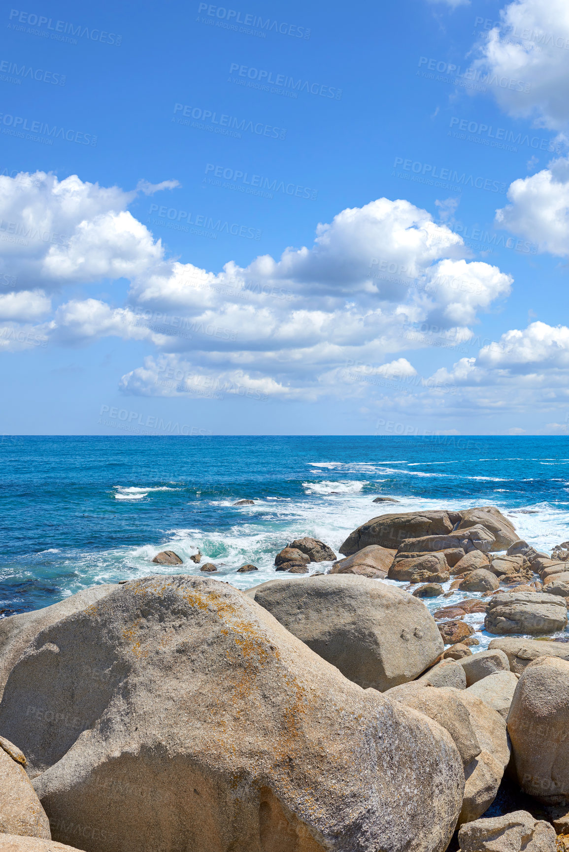 Buy stock photo Copyspace at sea with a cloudy blue sky background and rocky coast in Camps Bay, Cape Town, South Africa. Boulders at a beach shore across a majestic ocean. Scenic landscape for a summer holiday