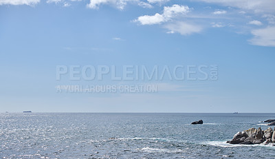 Buy stock photo Copy space at the sea with a cloudy blue sky background above the horizon. Calm ocean waters on the surface of an empty a beach. Peaceful coastal landscape for a relaxing and zen summer getaway