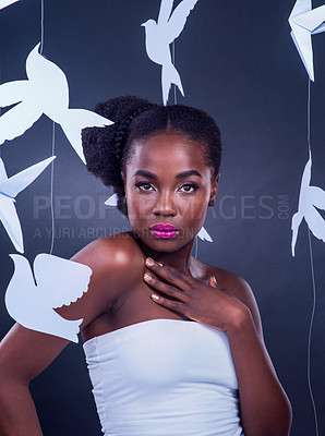 Buy stock photo Studio portrait of a beautiful young woman posing with paper birds against a black background